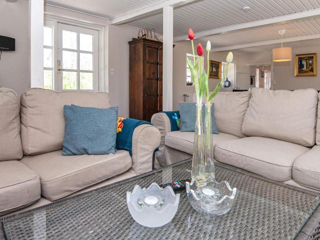 ein Wohnzimmer mit einem Sofa und einer Vase mit Blumen auf dem Tisch in der Unterkunft 7 person holiday home in Grenaa in Grenå