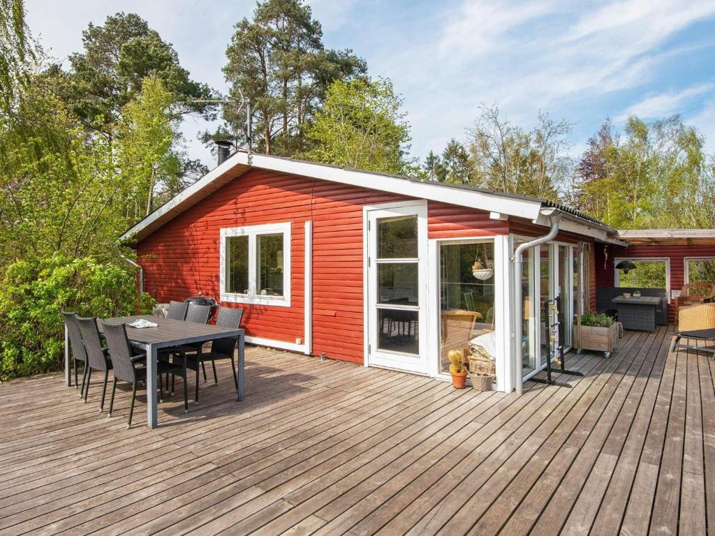 ein rotes Haus mit einer Terrasse mit einem Tisch und Stühlen in der Unterkunft 6 person holiday home in R nde in Rønde