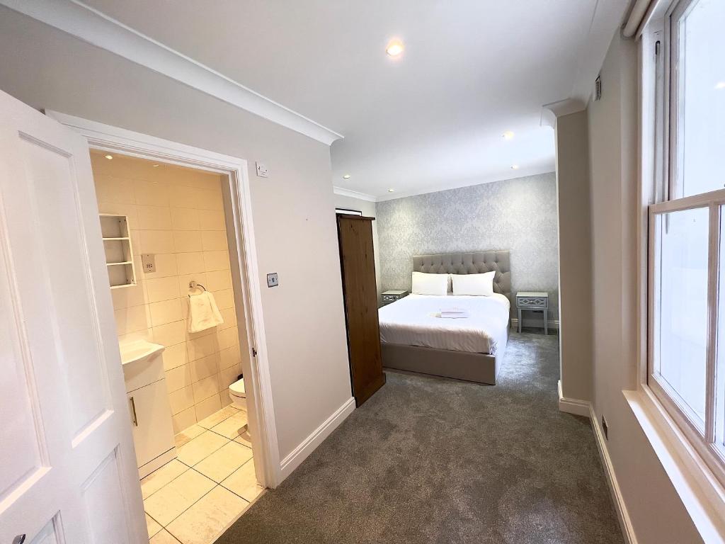a bedroom with a bed and a bathroom with a window at The Beverley Apartments London - Victoria in London