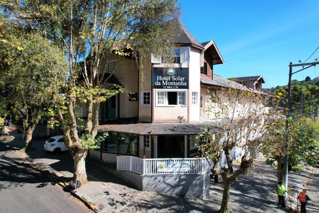 a building with a sign for a hotel with trees at Hotel Solar da Montanha in Campos do Jordão