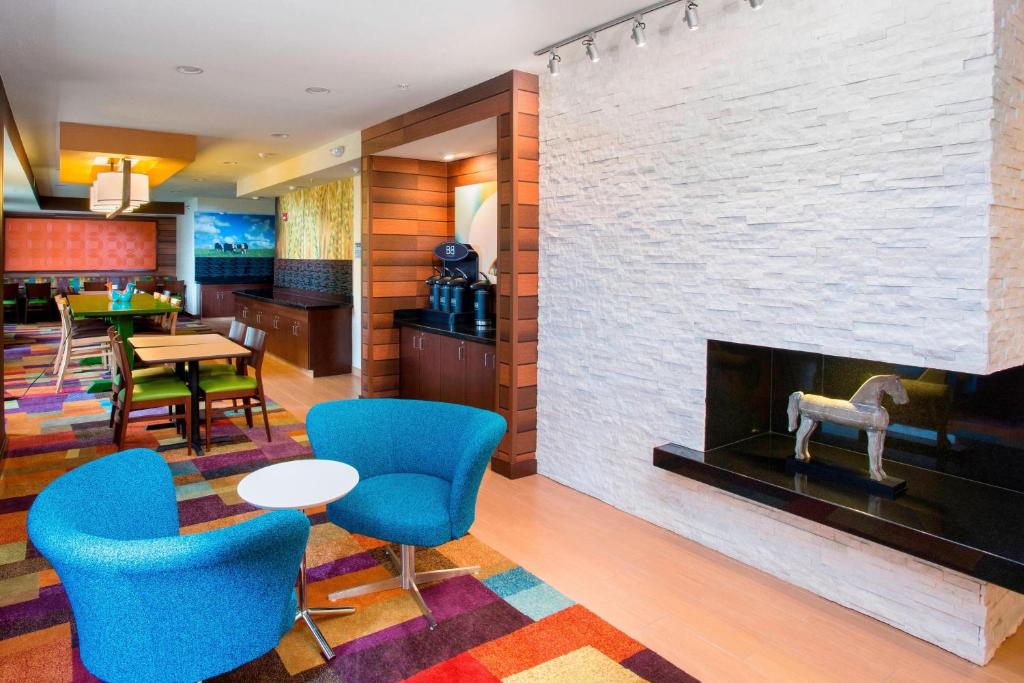 a lobby with a fireplace and blue chairs at Fairfield Inn & Suites by Marriott Quincy in Quincy