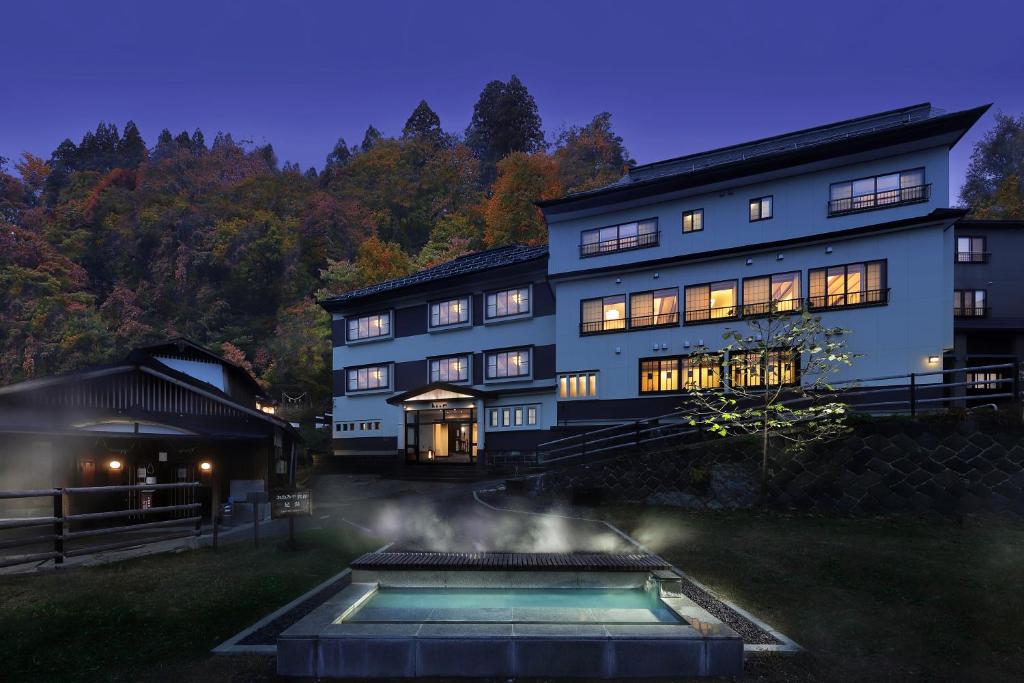 une grande maison avec une piscine en face de celle-ci dans l'établissement Zao Onsen Omiya Ryokan, à Zao Onsen