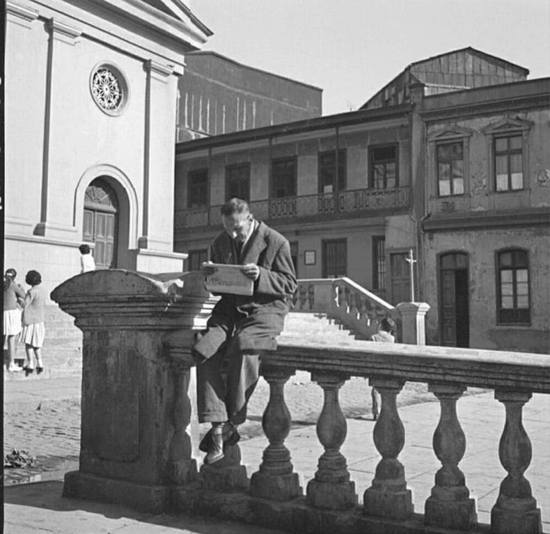 um homem sentado numa cerca com uma caixa em Histórica y cómoda em Valparaíso
