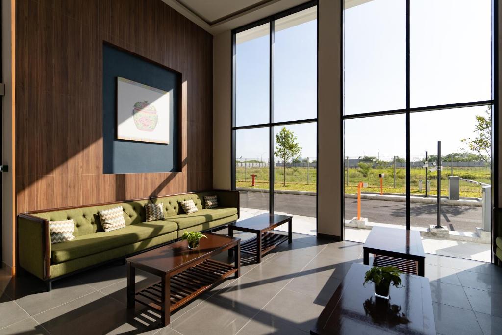a living room with a green couch and large windows at Amber Cove Impression City Melaka By Dawn Stay Free Netflix in Melaka