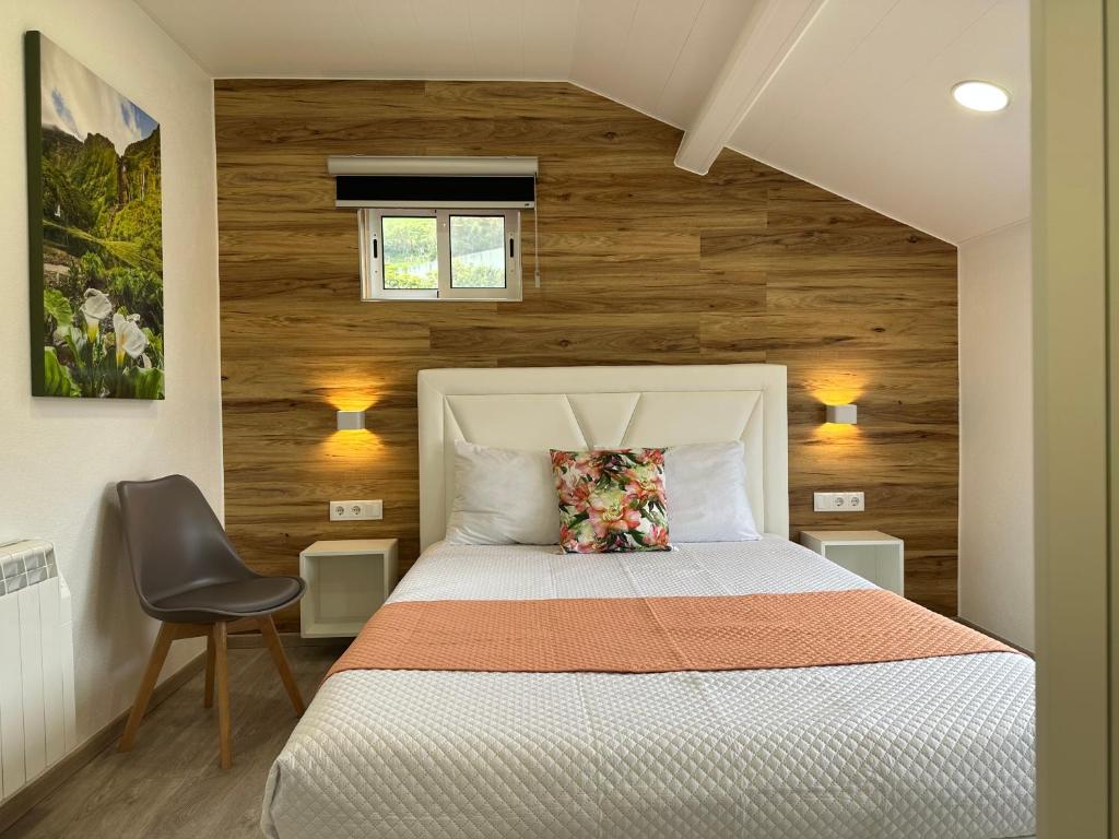 サンタ・クルス・ダス・フローレスにあるParadise Apartments IIIの白いベッドと木製の壁が備わるベッドルーム1室が備わります。
