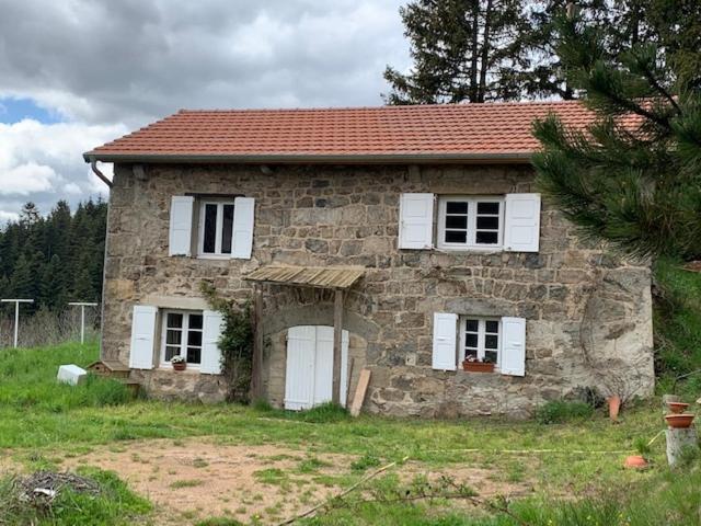 una casa in pietra con finestre bianche e tetto rosso di Ancienne petite ferme rénovée a Saint-Régis-du-Coin