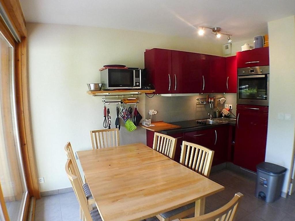 una cucina con tavolo in legno e una cucina con armadi rossi di Appartement Samoëns, 3 pièces, 4 personnes - FR-1-629-48 a Samoëns