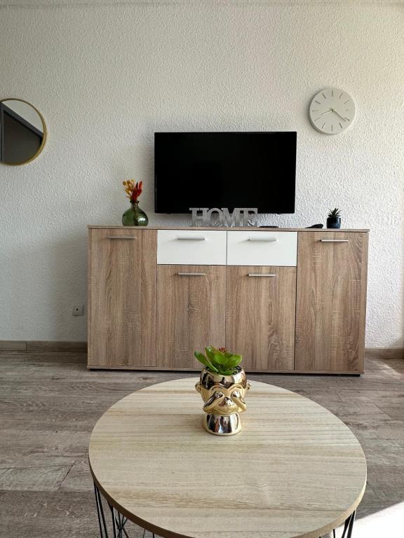 a living room with a table with a television on a cabinet at Studio COSY à deux pas de la PLAGE ! in Gruissan