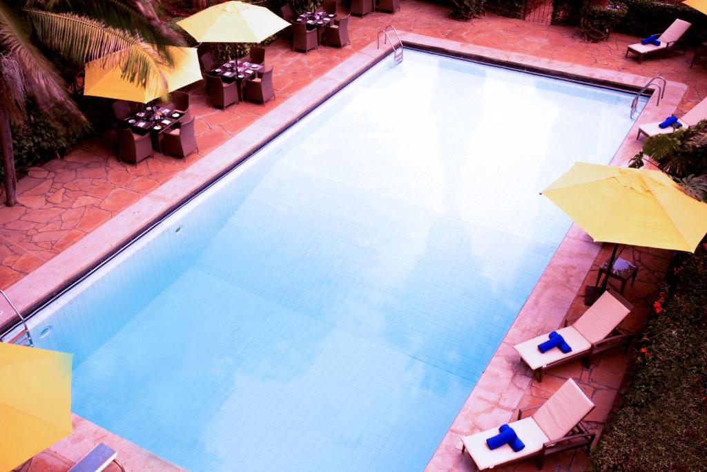 an overhead view of a swimming pool with chairs and umbrellas at Bidwood Suite Hotel in Nairobi