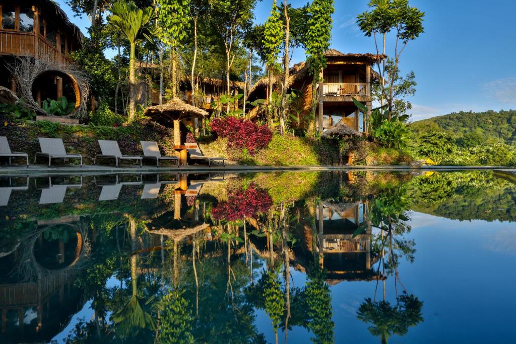 a resort pool with chairs and a house in the background at Pu Luong Natura in Pu Luong