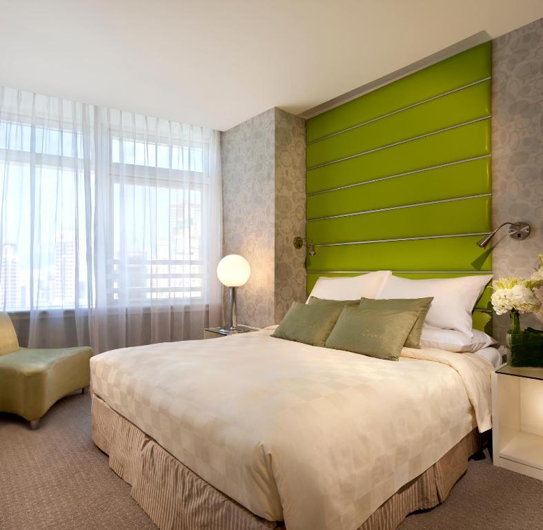 a bedroom with a large bed with a green headboard at Cosmo Hotel Hong Kong in Hong Kong