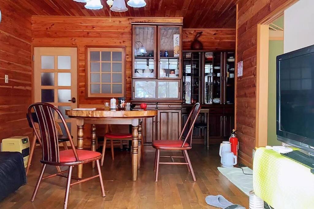 comedor con mesa, sillas y TV en 一番館※温泉街に近く、心が落ち着く別荘地同樺順荘, en Kusatsu