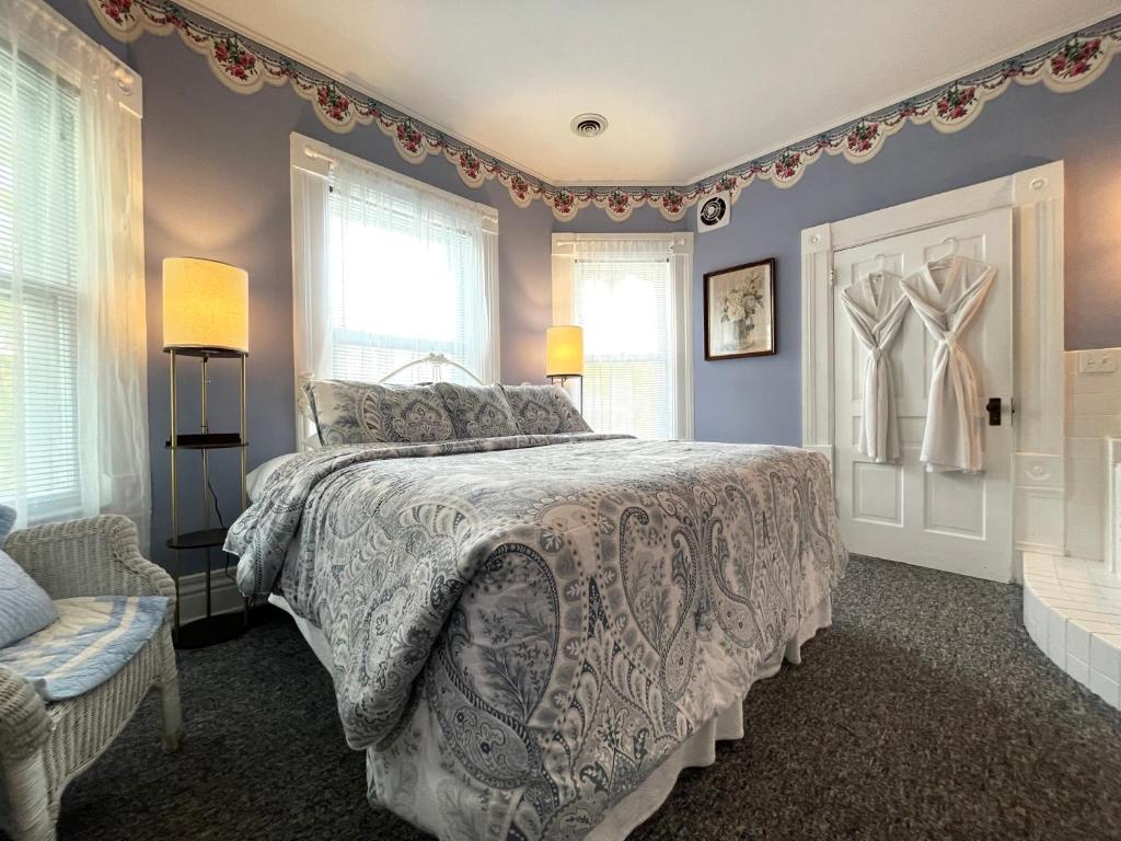 a bedroom with a bed and a chair and windows at White Rose Inns & Motel in Wisconsin Dells