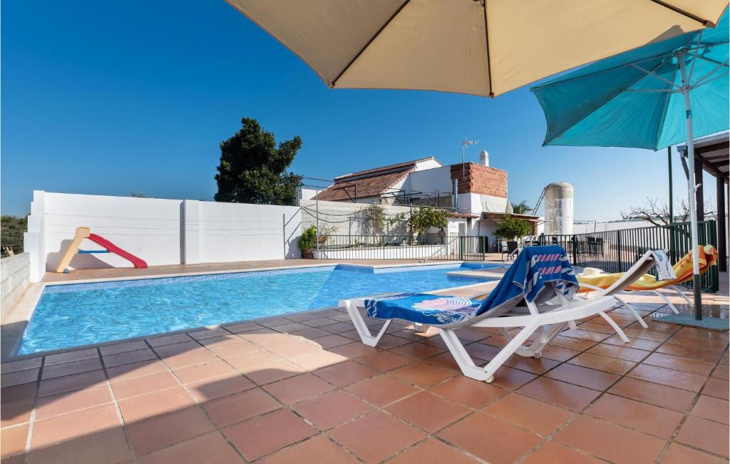 a swimming pool with two chairs and an umbrella at Nice Home In Baena With Outdoor Swimming Pool in Baena
