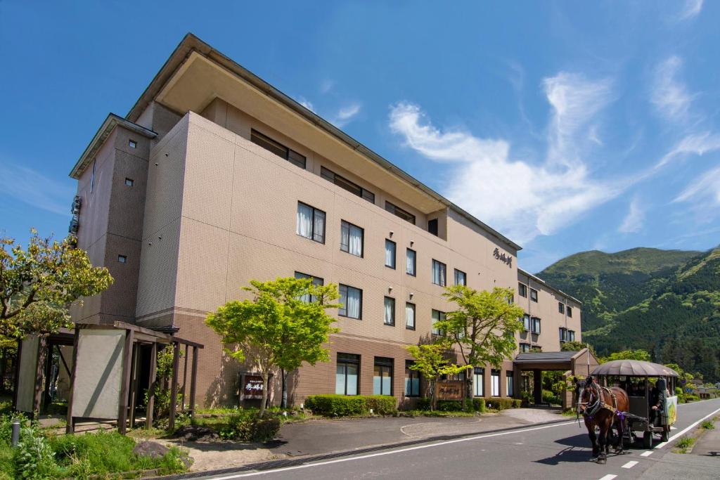 une calèche tirée par des chevaux devant un bâtiment dans l'établissement Yufuin Hotel Shuhokan, à Yufu