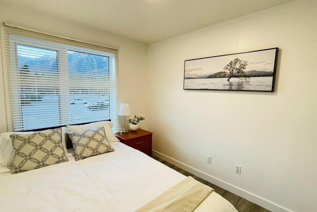 a bedroom with a white bed and a window at Unit #204 Cozy Mountain View 2BR in Canmore Downtown in Canmore