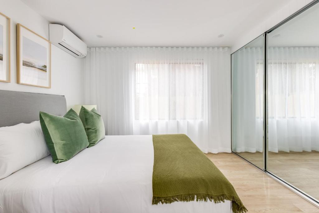 1 dormitorio con 1 cama blanca grande con almohadas verdes en Kahlo Bondi - Luxury Escape - 1 Bedroom Furnished Apartments en Sídney