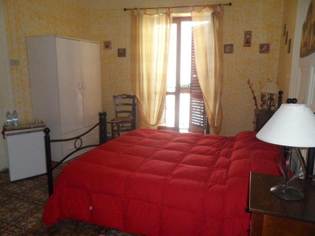 a bedroom with a red bed and a large window at B&B Il Vecchio Messina in Trapani