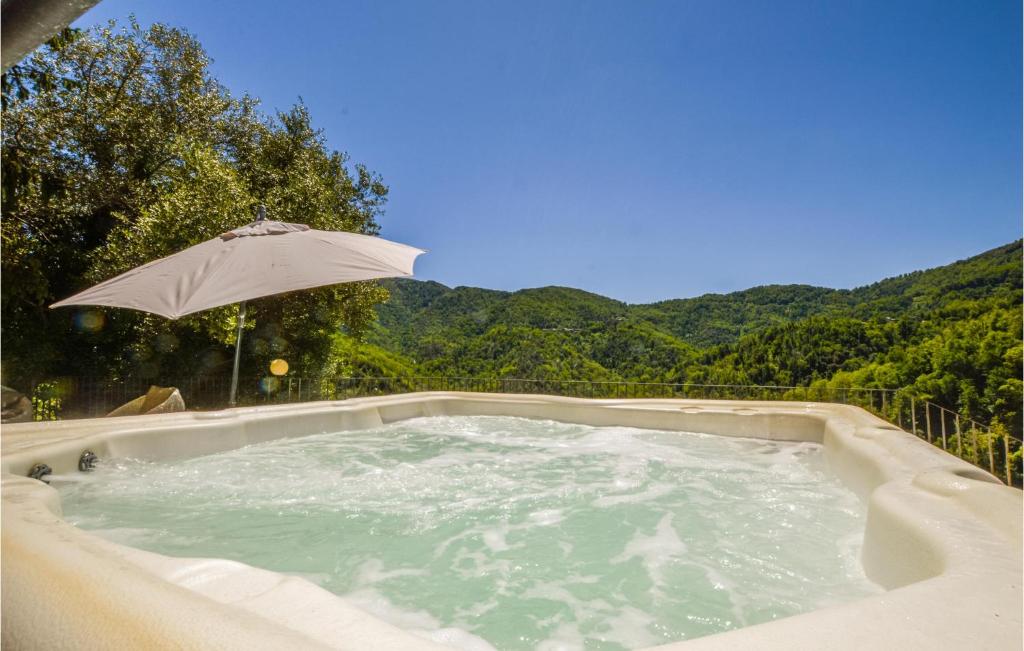 bañera de hidromasaje con sombrilla y montañas de fondo en Nice Apartment In Carcheto Brustico With House A Mountain View, en Carcheto