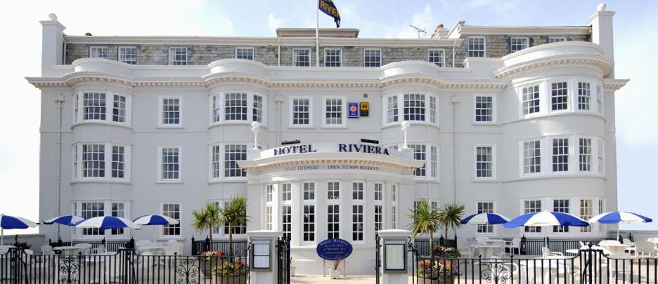 un edificio blanco con sombrillas azules delante en Hotel Riviera en Sidmouth