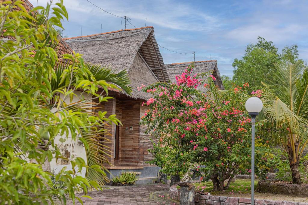 una casa de ladrillo con flores rosas delante de ella en Batang Golden Hills en Nusa Penida