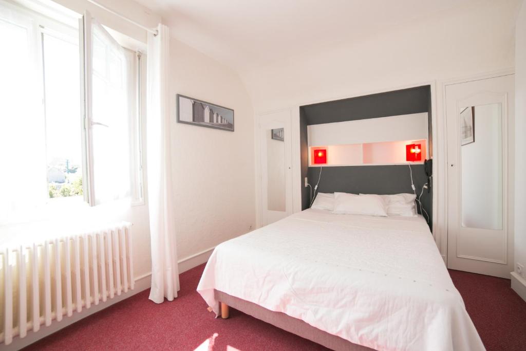 um quarto com uma cama branca e uma janela em Hôtel An Ti Gwenn em Carnac