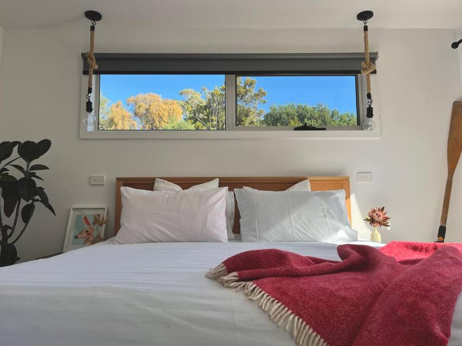 a bedroom with a large white bed with a window at Viola - Seaside Retreat in Coles Bay