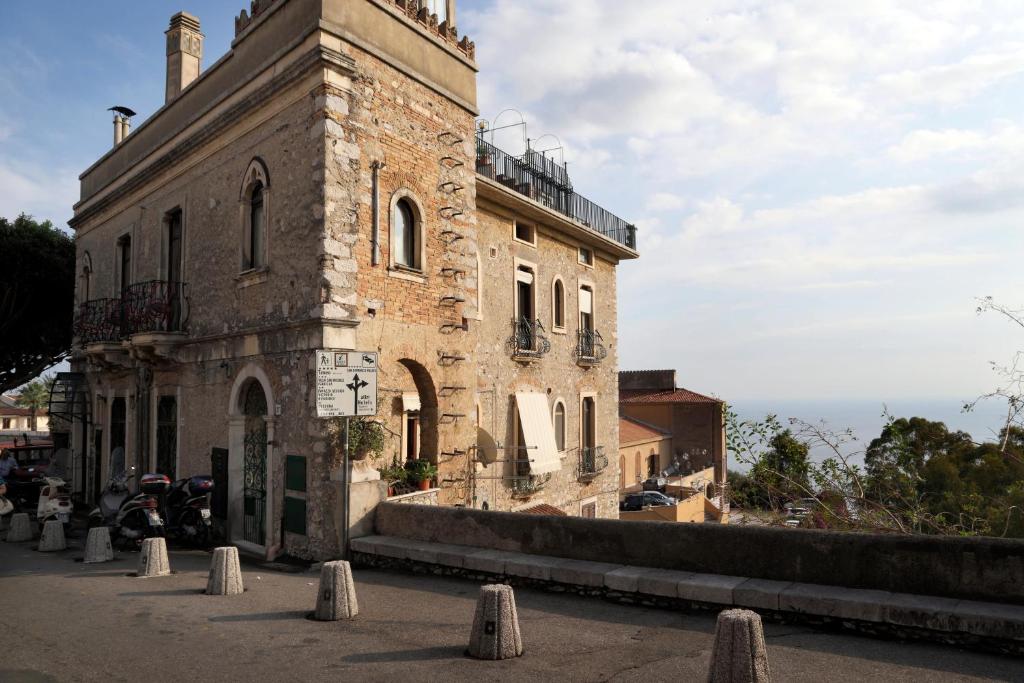 an old brick building with a tower on a street at Casa Costa in Taormina