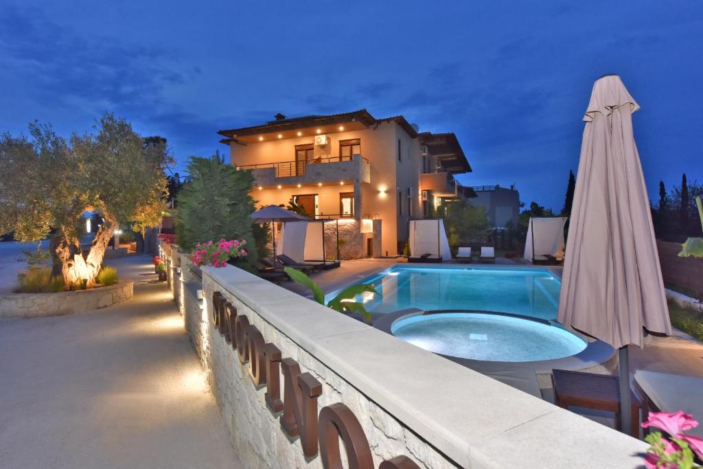 a house with a swimming pool and an umbrella at Sinodinos Deluxe Apartments in Afitos