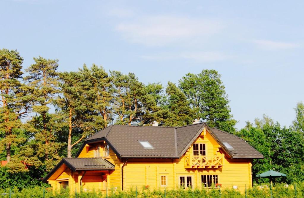 una casa amarilla con techo negro en Eco-House Ainaži, en Ainaži
