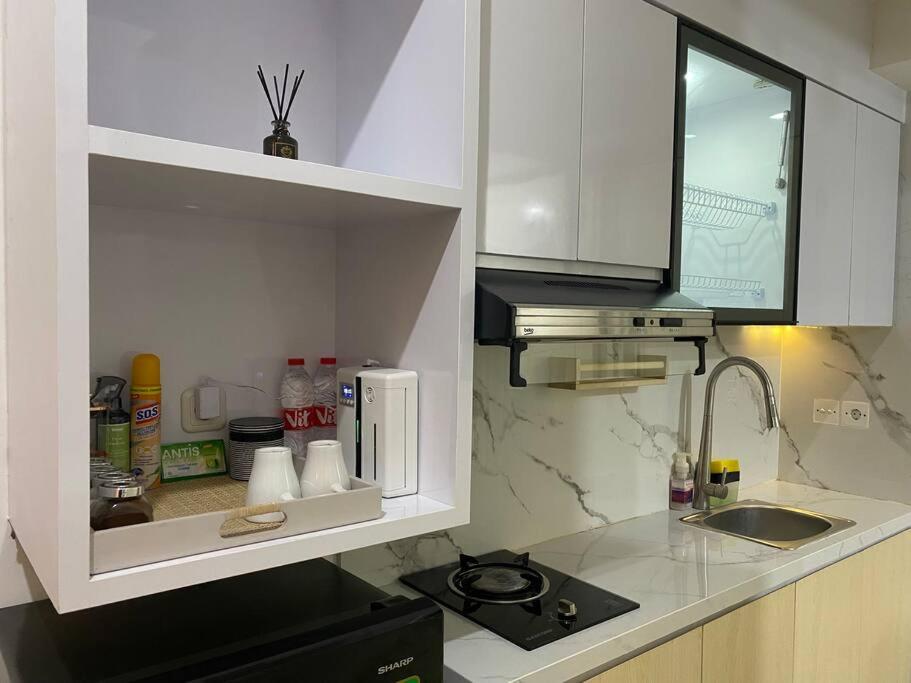 a kitchen with white cabinets and a sink and a microwave at Alexa at Tanglin Apartemen in Surabaya