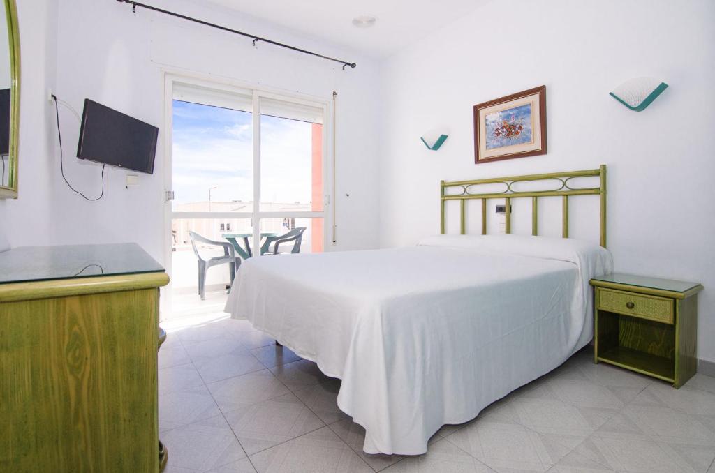 a bedroom with a white bed and a balcony at Hostal Manolo in Garrucha