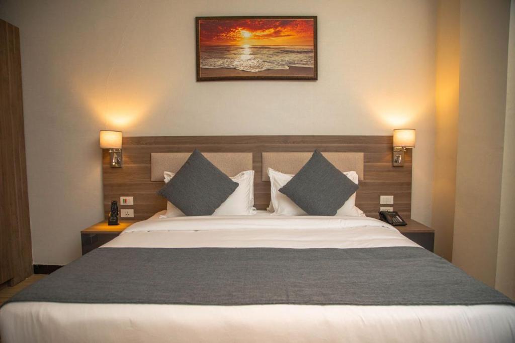 a bedroom with a large bed with two lamps on the wall at Triple E Hotel and Spa in Addis Ababa