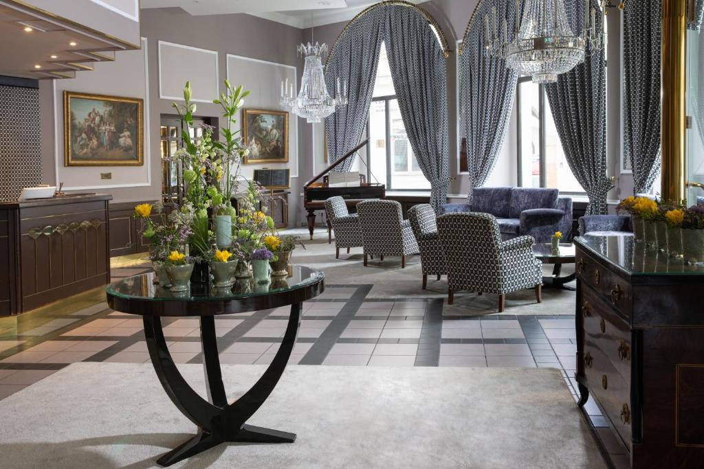 eine Lobby mit einem Tisch mit Blumen darauf in der Unterkunft Grand Hotel Bohemia in Prag