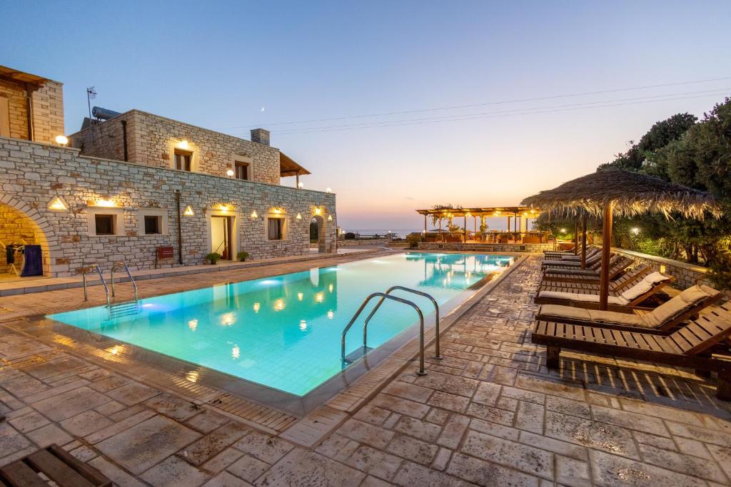 een groot zwembad met stoelen en een gebouw bij Avgerinos Village in Agiassos