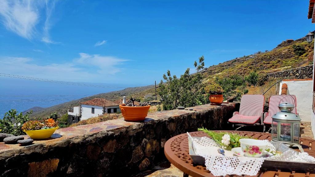 a table and chairs on a stone wall with a view of the ocean at Rincón de Mercedes in Fuencaliente de la Palma