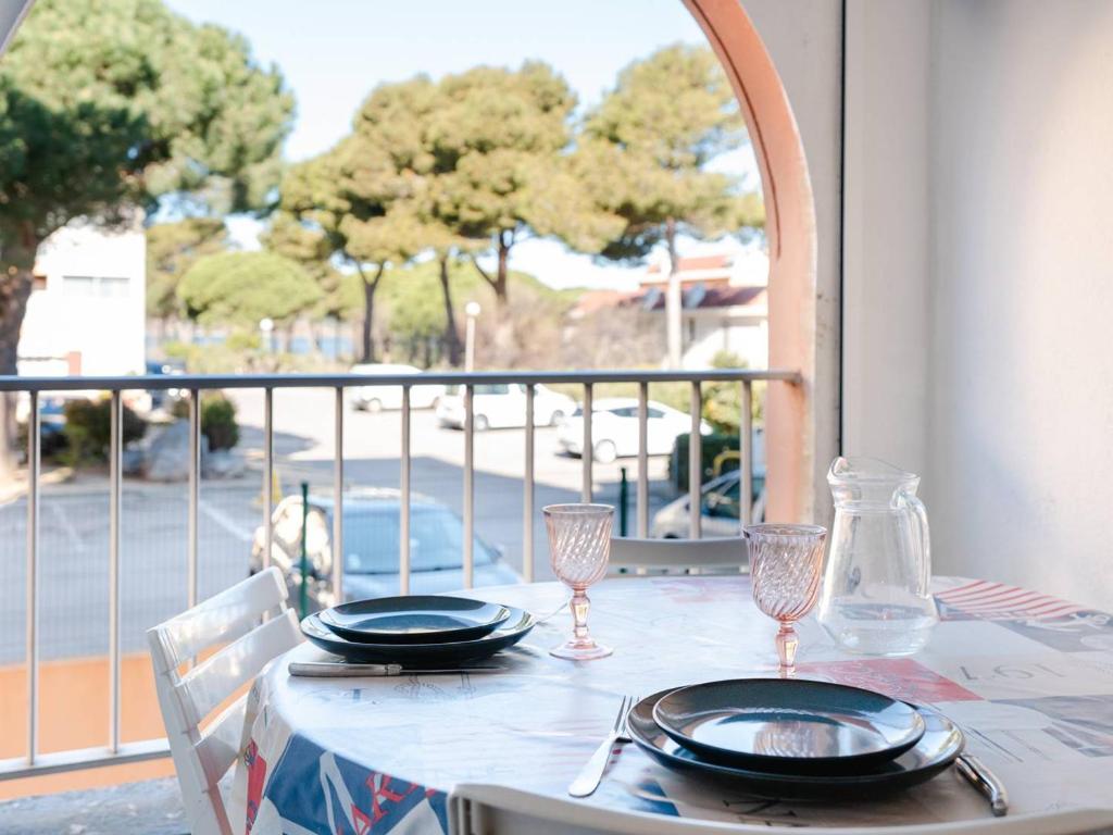 une table avec des assiettes et des verres à vin sur un balcon dans l'établissement T2 avec Piscine à Gruissan - Proche Plage et Commerces - FR-1-409A-14, à Gruissan