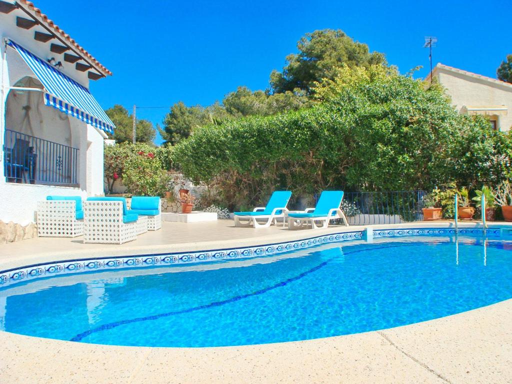 a swimming pool with blue chairs and a house at Villa Alejandria in Moraira