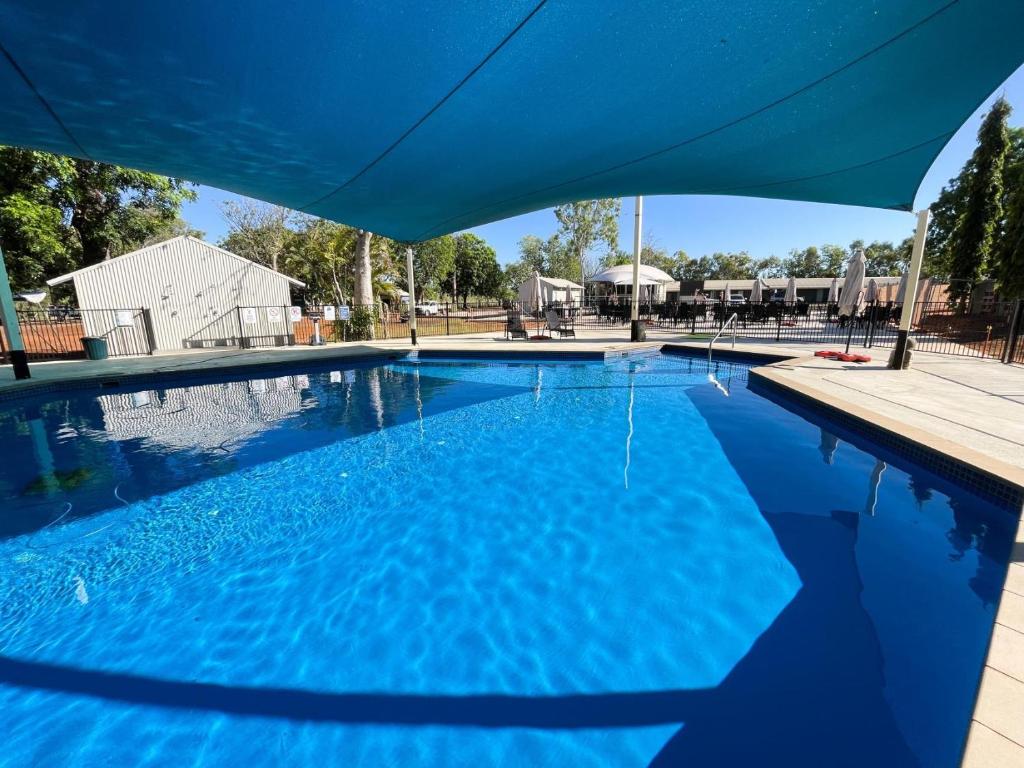 a swimming pool with a blue umbrella over it at Lily Lagoon Resort in Kununurra