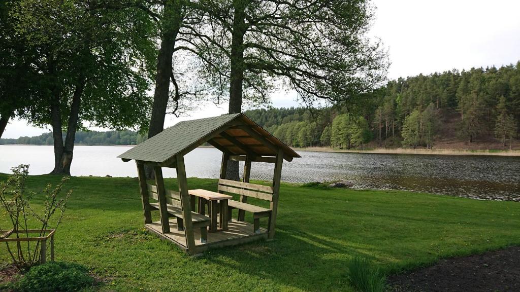 a gazebo sitting on the grass near a lake at Lūšių vėjas in Palūšė