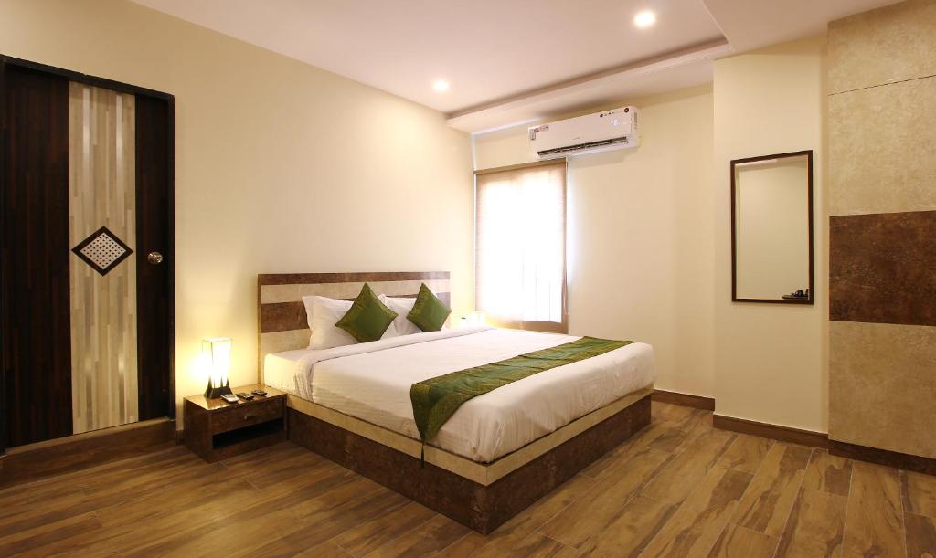 a bedroom with a bed and a window and a mirror at Treebo Trend Address Inn in Hyderabad