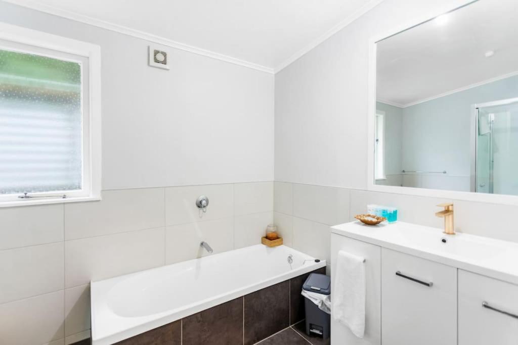 a white bathroom with a sink and a mirror at Spacious Family Retreat in City - Netflix - WiFi in Auckland