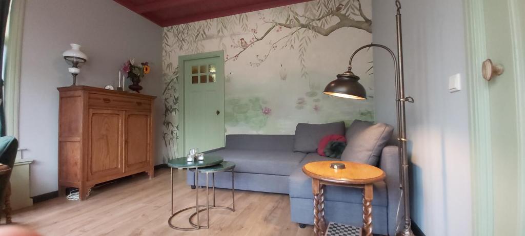 ein Wohnzimmer mit einem blauen Sofa und einem Tisch in der Unterkunft B en B Op Steendam, Het Voorhuis in Steendam