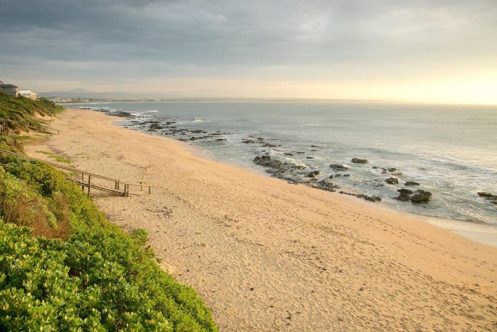 a sandy beach with rocks in the water at SEEMEEU in Jeffreys Bay