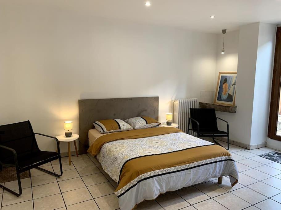 a bedroom with a large bed and two chairs at Gîte des Anciennes Salines Nationales in Montmorot