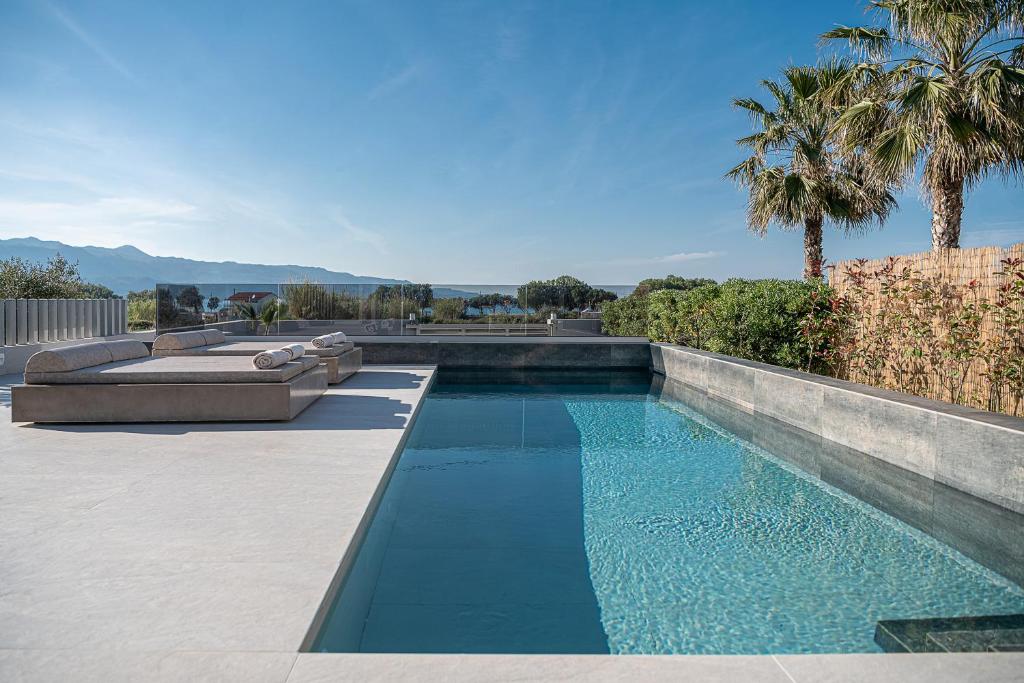 a swimming pool with blue water and palm trees at Fivi Luxury Villa, with Heated Pool & SeaViews, By ThinkVilla in Tavronitis