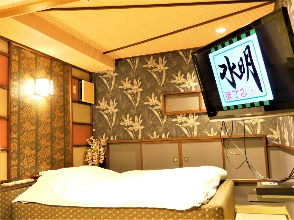 a room with a tv and a bed in a room at ホテル水明 in Koriyama