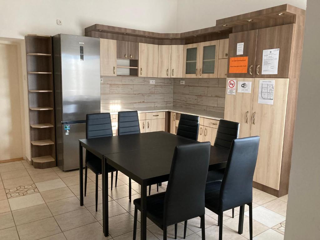 a kitchen with a black table and chairs and a refrigerator at Gogol24 in Szeged
