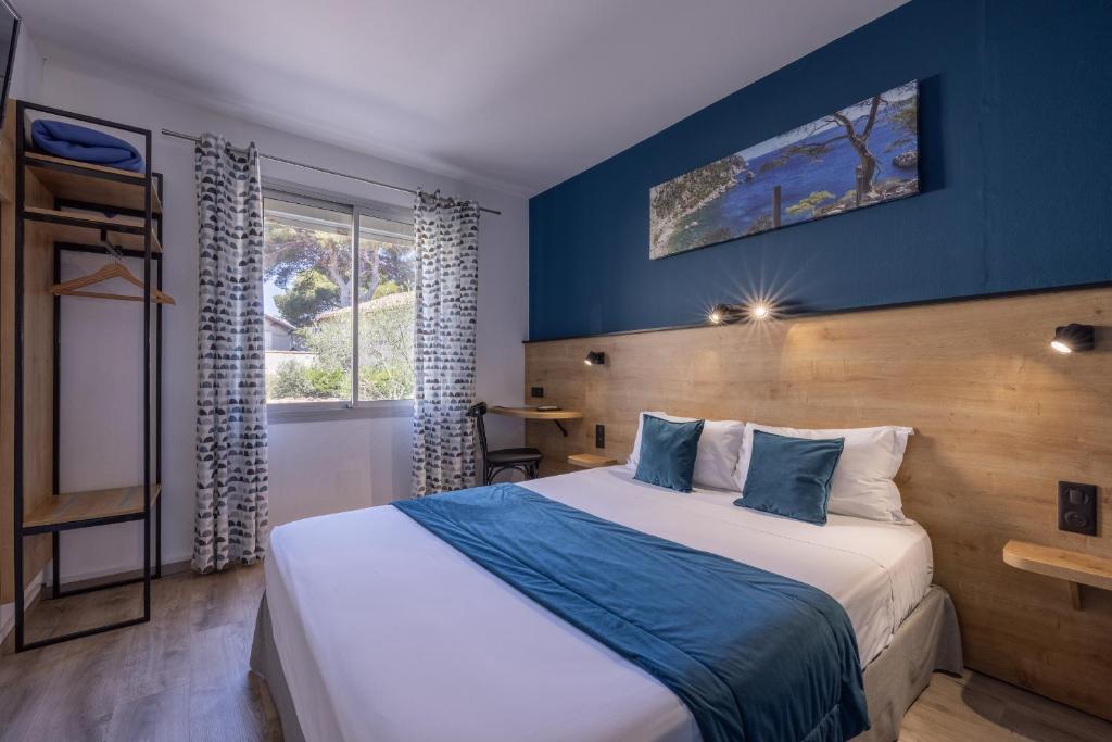 a bedroom with a large bed with a blue wall at The Originals City, Hôtel Azur, Fos-sur-Mer in Fos-sur-Mer