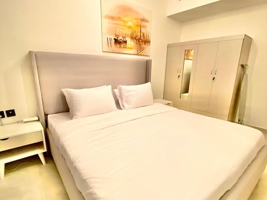 a bedroom with a large white bed with a night stand at Downtown Dubai 7 minutes away from Burj Khalifa in Dubai
